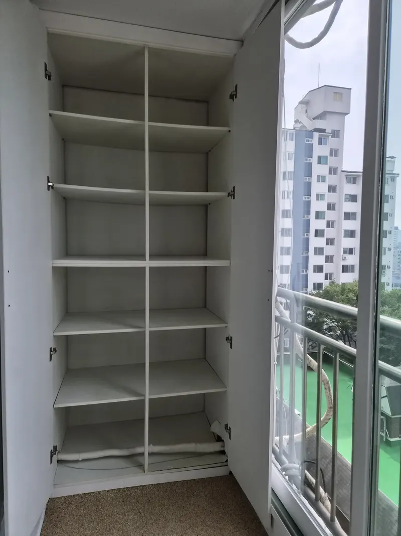 수납장문짝교체 시공 현장 — 선반이 있는 베란다 수납장 내부